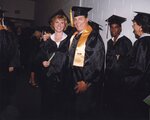 Two faculty/staff members posing in commencement regalia